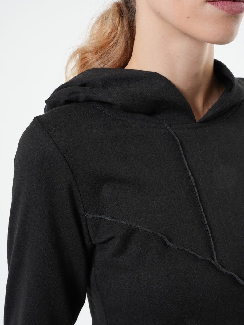 May include: Black long-sleeved hooded sweatshirt with a contrasting stitch detail on the front.