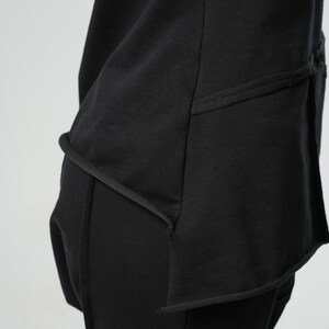 May include: Black long-sleeved shirt with a layered design and a curved hemline. The shirt has a relaxed fit and is made of a soft, comfortable fabric.