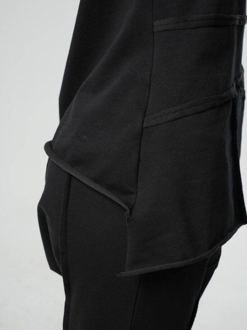 May include: Black long-sleeved shirt with a layered design and a curved hemline. The shirt has a relaxed fit and is made of a soft, comfortable fabric.