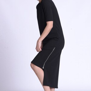 Puede incluir: Un vestido midi negro con cremallera lateral y mangas cortas. El vestido est&aacute; hecho de una tela suave y el&aacute;stica. La modelo lleva zapatillas negras y blancas.