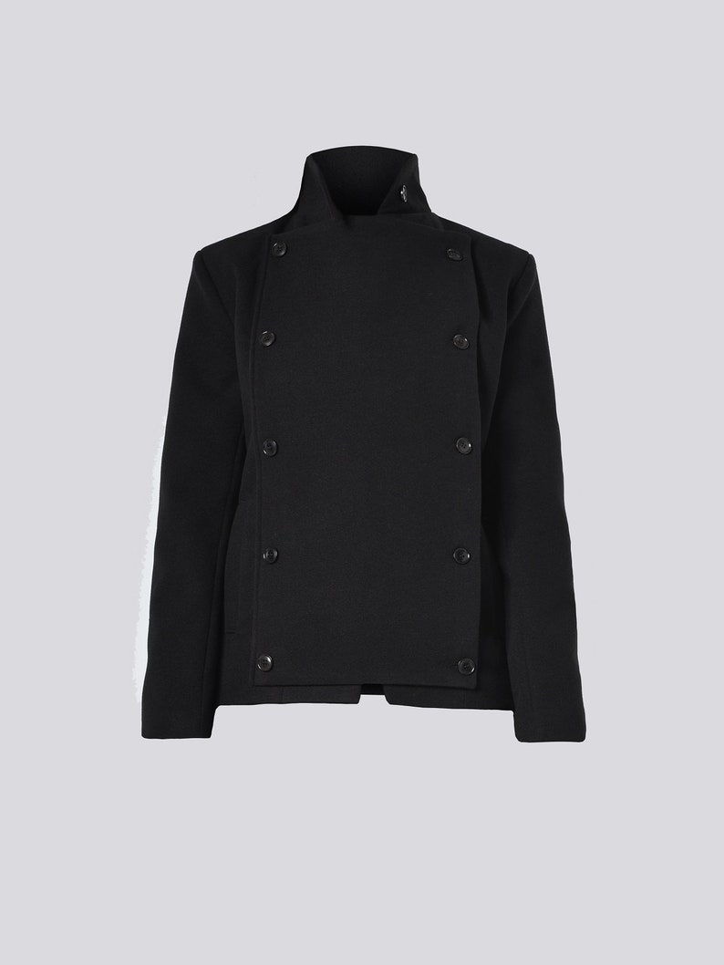 May include: A black jacket with a high collar and a double-breasted design. The jacket features six visible buttons and a tailored fit. The sleeves are long, and the fabric appears to be a textured wool blend.