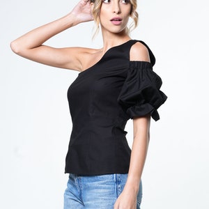 May include: A black one-shoulder top with a puff sleeve. The top has a fitted bodice and a relaxed fit through the body.