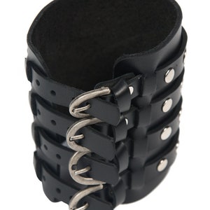 May include: Black leather cuff bracelet with multiple buckles and silver studs.