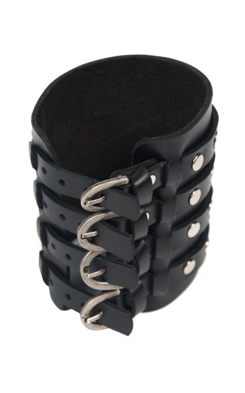 May include: Black leather cuff bracelet with multiple buckles and silver studs.