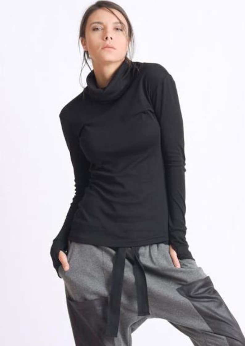 May include: A black long-sleeved shirt with a mock neck and thumbholes. The shirt is made of a soft, stretchy fabric and has a relaxed fit.