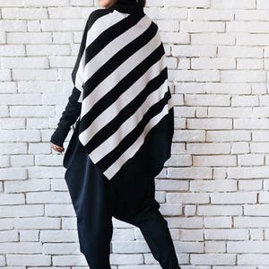 May include: A black and white striped tunic with a diagonal pattern. The tunic is worn over black pants.