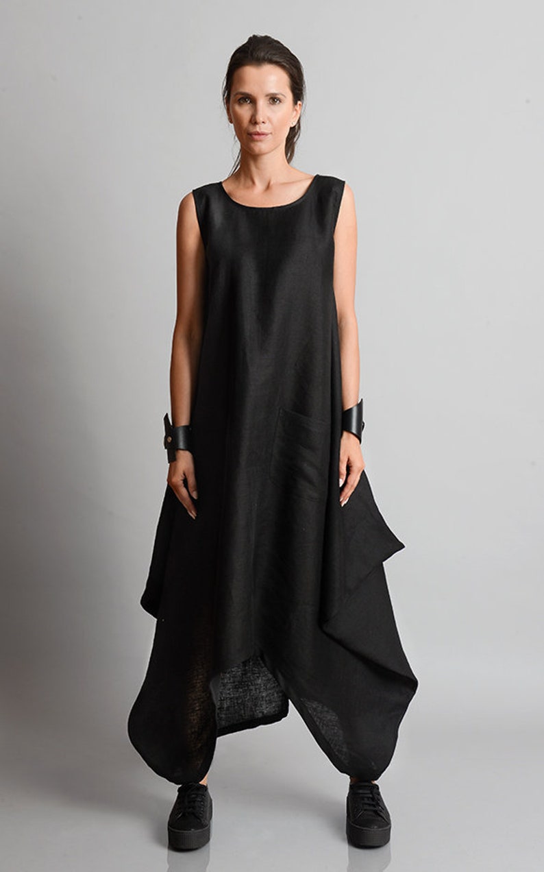 May include: A black linen dress with a loose, flowing silhouette. The dress has a scoop neckline and a sleeveless design. The hemline is asymmetrical, with a longer back and a shorter front. The dress is made of a soft, comfortable fabric and has a relaxed fit.