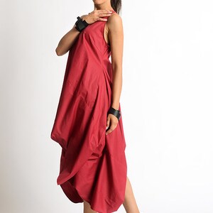 Peut inclure: Une femme portant une robe rouge sans manches avec une jupe pliss&eacute;e et des sandales &agrave; plateforme noires.