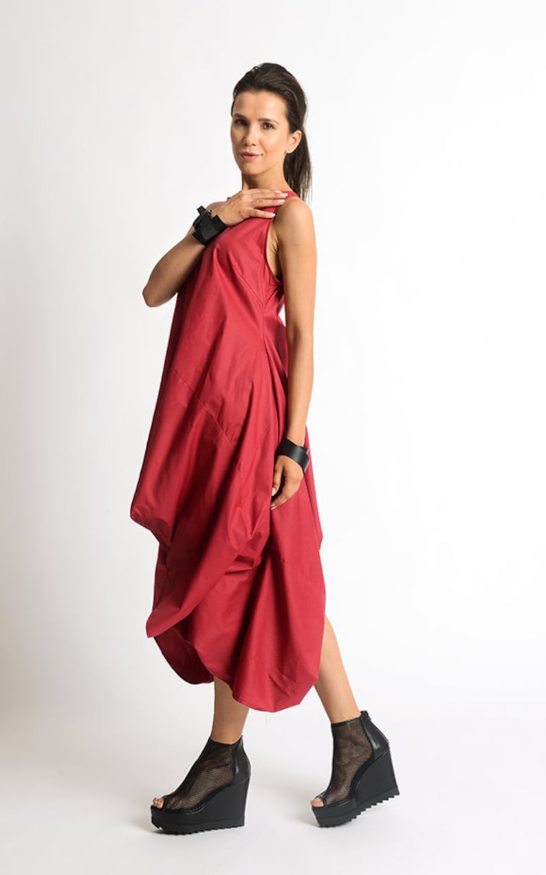 Peut inclure: Une femme portant une robe rouge sans manches avec une jupe pliss&eacute;e et des sandales &agrave; plateforme noires.