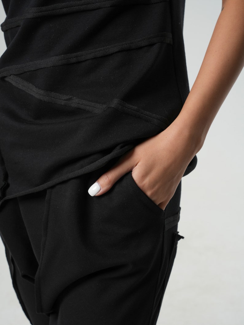 May include: Black pants with a pocket and a black top with a layered design.