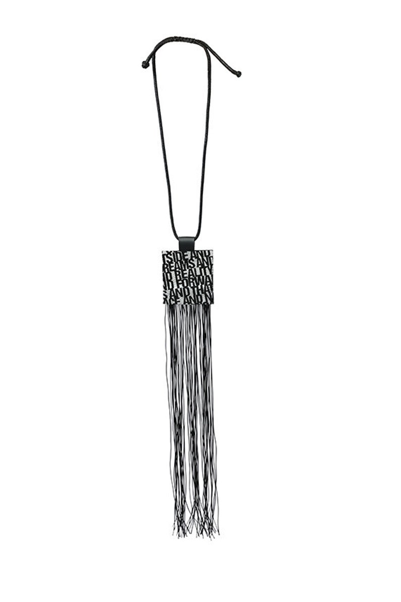Puede incluir: Collar negro con un colgante cuadrado con texto y una larga borla de hebras negras. El colgante tiene un fondo negro con texto blanco. El collar es de dise&ntilde;o sencillo, adecuado para varios atuendos.