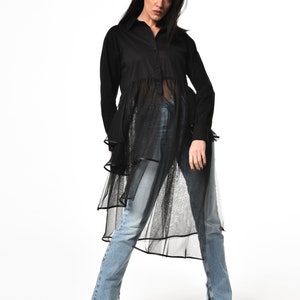 May include: A black long-sleeved shirt with a sheer overlay and a ruffled hem. The shirt is button-up and has a relaxed fit.