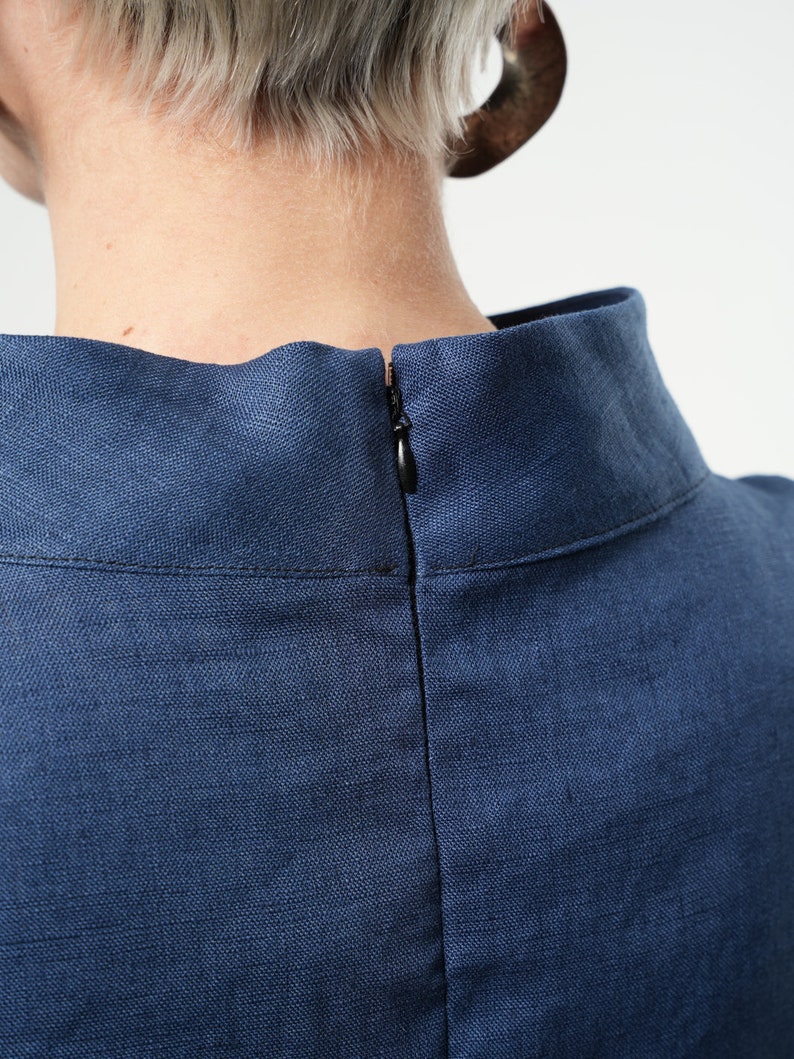 May include: A close-up of the back of a navy blue linen dress with a zip closure.