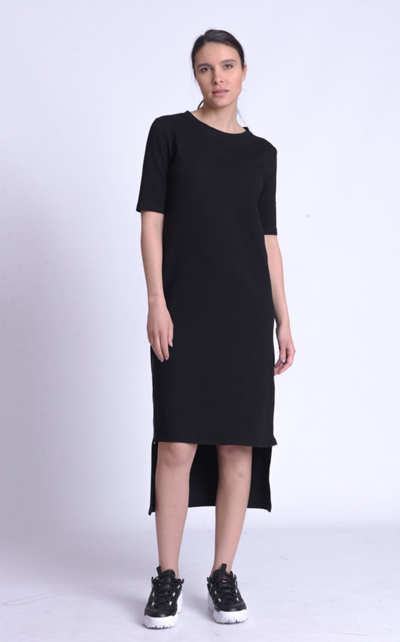 Puede incluir: Un vestido midi negro con un dobladillo alto-bajo. El vestido tiene un escote redondo y mangas cortas.