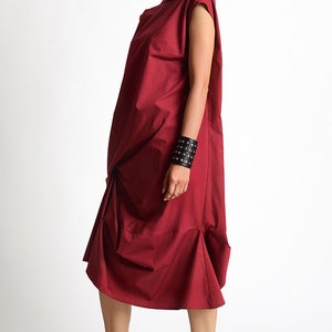 May include: A burgundy sleeveless dress with a high neckline and a gathered skirt. The dress is made of a soft, comfortable fabric and has a relaxed fit.