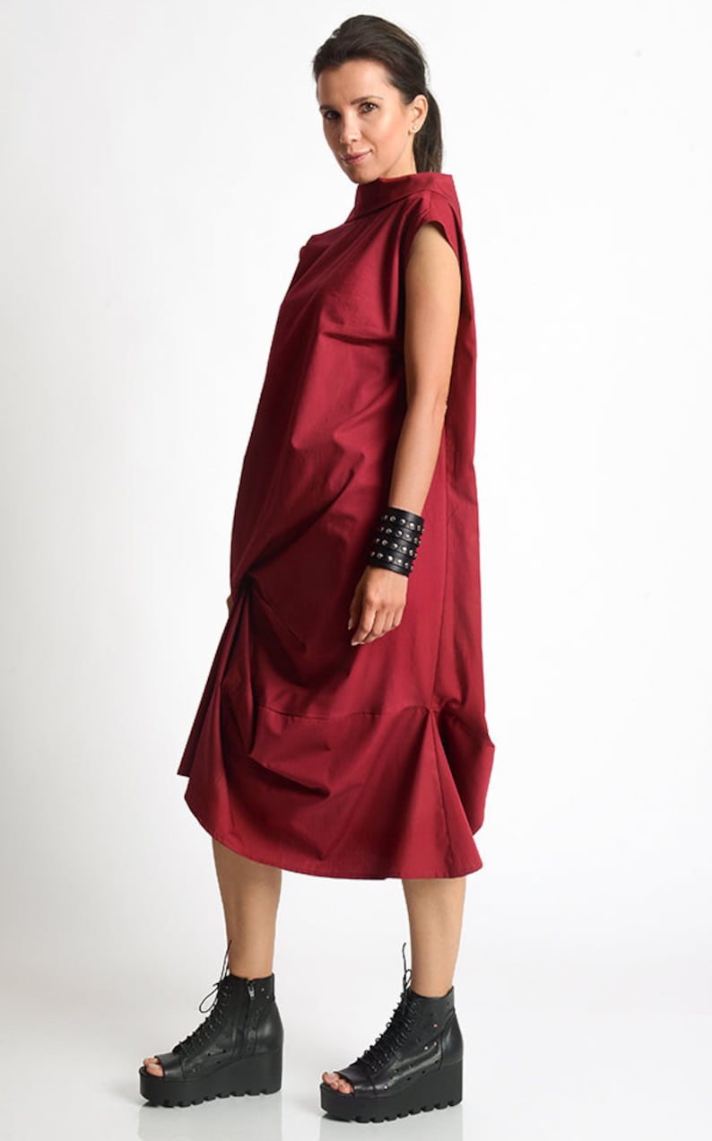 May include: A burgundy sleeveless dress with a high neckline and a gathered skirt. The dress is made of a soft, comfortable fabric and has a relaxed fit.