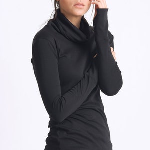 May include: A black mock neck shirt with long sleeves and a cowl neck. The shirt is made of a soft, stretchy fabric.