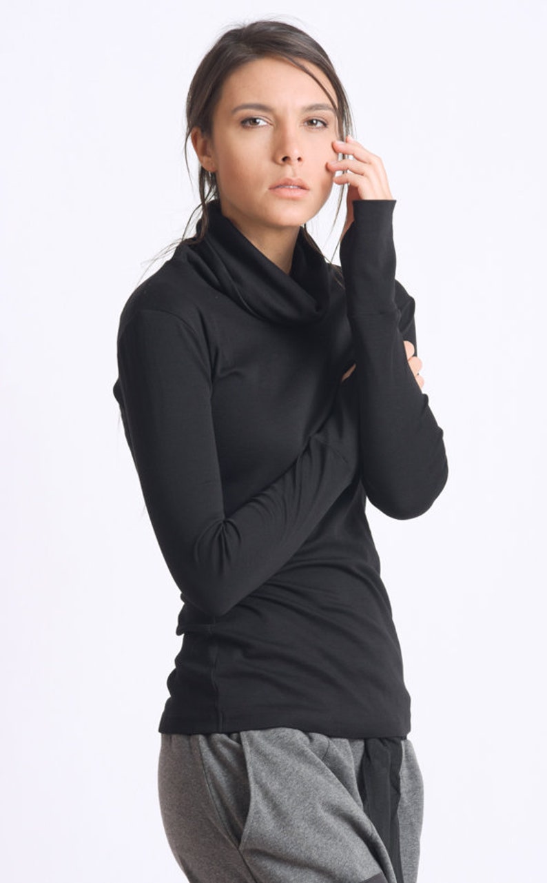May include: A black mock neck shirt with long sleeves and a cowl neck. The shirt is made of a soft, stretchy fabric.