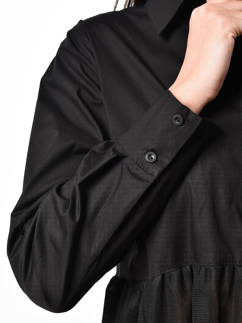 May include: Black long-sleeved shirt with a black tulle overlay. The shirt has a button-up collar and button cuffs.