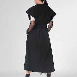 May include: A black sleeveless dress with a long skirt and a belt. The dress has a simple design and is made of a soft, flowing fabric.