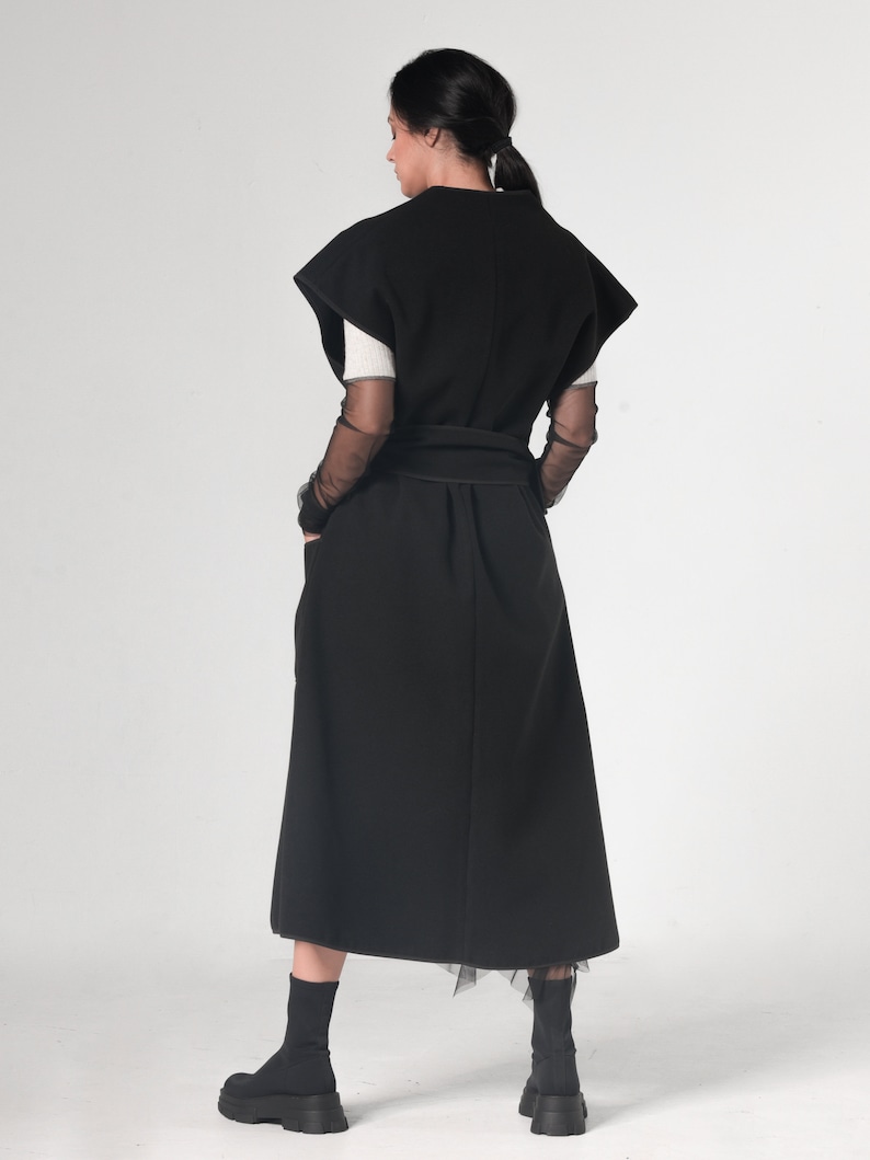 May include: A black sleeveless dress with a long skirt and a belt. The dress has a simple design and is made of a soft, flowing fabric.