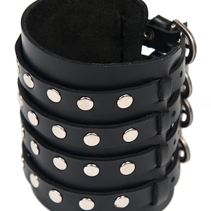 May include: Black leather bracelet with silver studs and a buckle closure. The bracelet is made of four layers of leather and has a total of 16 studs.