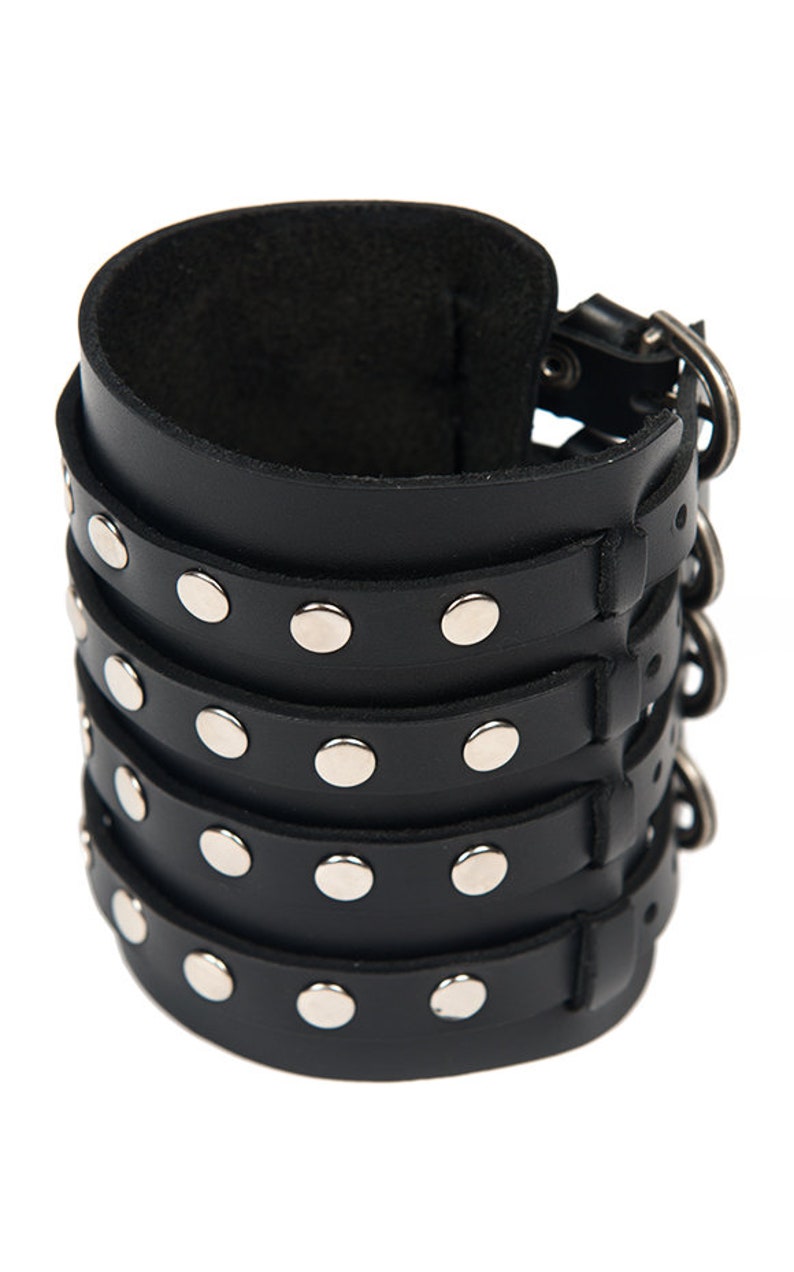 May include: Black leather bracelet with silver studs and a buckle closure. The bracelet is made of four layers of leather and has a total of 16 studs.