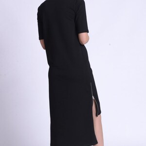 Puede incluir: Un vestido midi negro con un detalle de cremallera lateral. El vestido est&aacute; hecho de una tela suave y c&oacute;moda y tiene un ajuste holgado.