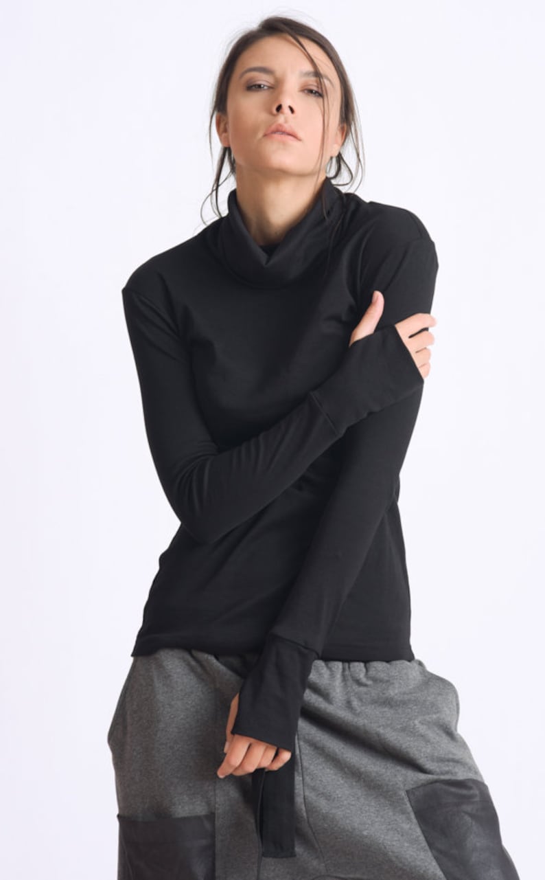 May include: A black long-sleeved shirt with a mock neck and thumbholes. The shirt is made of a soft, stretchy fabric.