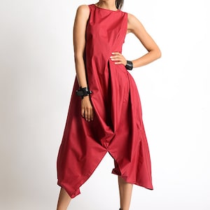 Peut inclure: Une combinaison rouge sans manches &agrave; la coupe ample et fluide. La combinaison a une jambe large et une taille fronc&eacute;e. Le mannequin porte des talons compens&eacute;s noirs.