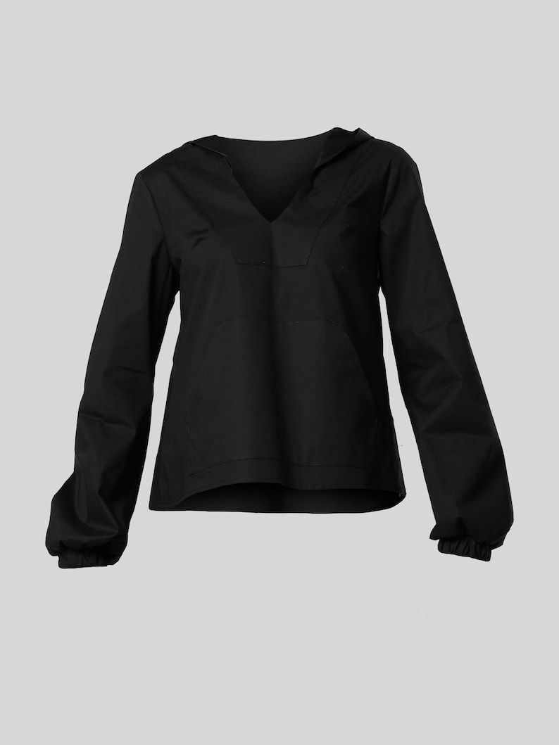 May include: A black hooded top with long sleeves and a V-neck. The sleeves have elasticated cuffs. The shirt is made of a plain, solid fabric. The design is casual and comfortable.
