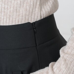 May include: Black skirt with a zipper closure in the back. The skirt is made of a smooth, wrinkle-resistant fabric.