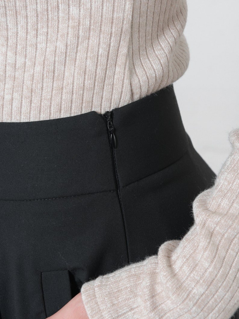 May include: Black skirt with a zipper closure in the back. The skirt is made of a smooth, wrinkle-resistant fabric.