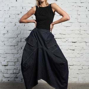 May include: A dark blue denim skirt with large pockets and a loose, flowing silhouette. The skirt is asymmetrical and has a high waist.