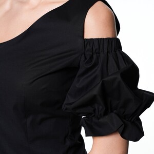 May include: Black one-shoulder top with a cold shoulder design and a ruffled puff sleeve.