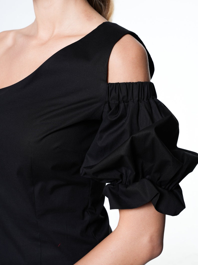May include: Black one-shoulder top with a cold shoulder design and a ruffled puff sleeve.
