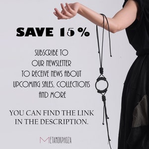 May include: A black leather necklace with a circular pendant and long tassels. The text "SAVE 15%" is displayed above the necklace. The text "SUBSCRIBE TO OUR NEWSLETTER TO RECEIVE NEWS ABOUT UPCOMING SALES, COLLECTIONS AND MORE YOU CAN FIND THE LINK IN THE DESCRIPTION. METAMORPHOZA" is displayed below the necklace.