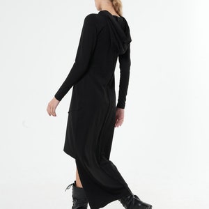 May include: Black hooded maxi dress with a long sleeve and a side slit. The dress is made of a soft, stretchy fabric and has a relaxed fit.