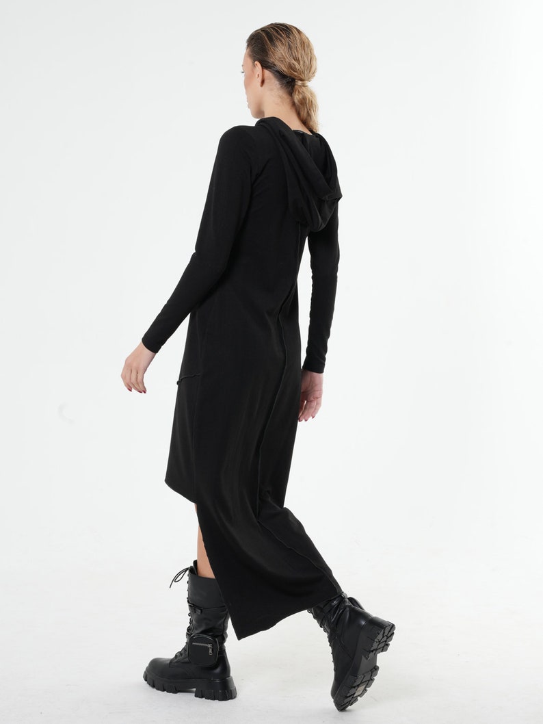 May include: Black hooded maxi dress with a long sleeve and a side slit. The dress is made of a soft, stretchy fabric and has a relaxed fit.