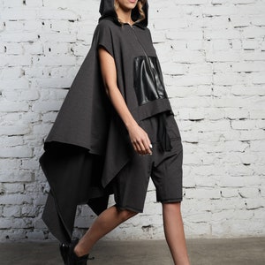 May include: A gray hooded top with a black leather panel and matching gray shorts. The top has a long, flowing cape-like back.