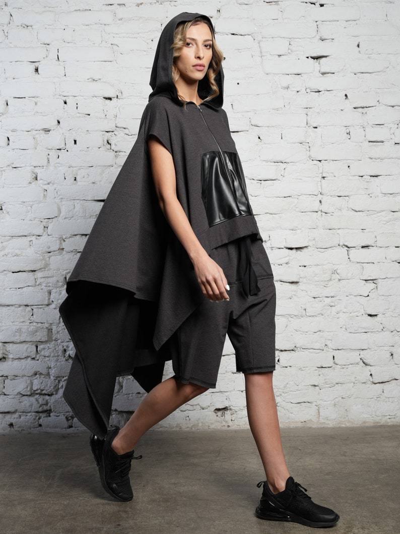 May include: A gray hooded top with a black leather panel and matching gray shorts. The top has a long, flowing cape-like back.