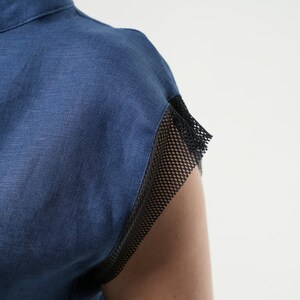 May include: A blue linen shirt with a black mesh trim on the sleeves.