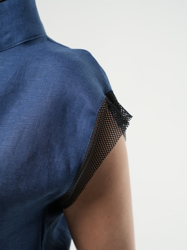 May include: A blue linen shirt with a black mesh trim on the sleeves.