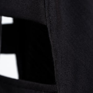 May include: Close-up of black fabric with a seam running down the side. The fabric has a slight sheen and a smooth texture.
