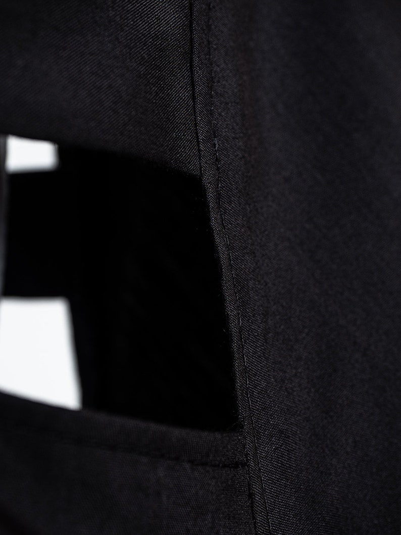May include: Close-up of black fabric with a seam running down the side. The fabric has a slight sheen and a smooth texture.