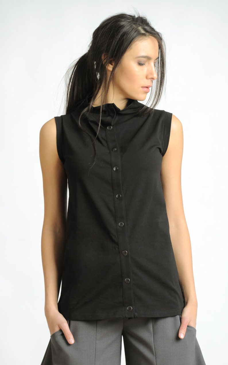 May include: A black sleeveless shirt with a mock neck and a button-up front. The shirt has a relaxed fit and is made of a soft, comfortable fabric.