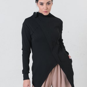 Puede incluir: Una camisa negra de manga larga con cuello alto y un detalle de costura en diagonal. La camisa está hecha de una tela suave y elástica y tiene un ajuste holgado.