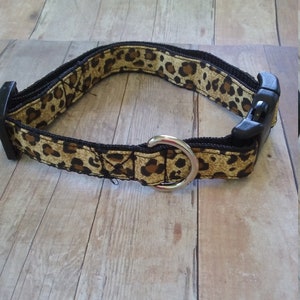 May include: A brown and black leopard print dog collar with a black buckle and silver D-ring.