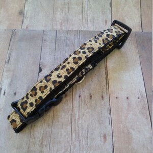 May include: A black and brown leopard print dog collar with a black plastic buckle.