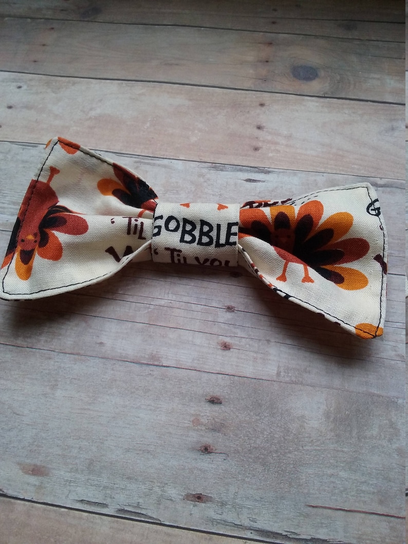 May include: A white bow tie with a brown and orange turkey print and the text "Til Gobble Til You"